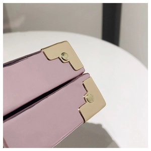 Close-up of pink sequin bag featuring gold metal corner protectors and rivet detail