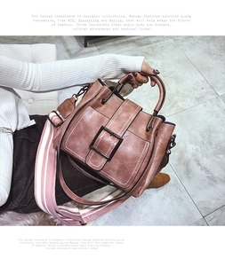 Detail of greyish pink bucket bag with wide striped strap and metal buckle decorative