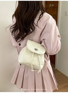 Close-up of quilted cream mini backpack with silver turn-lock and chain strap detail