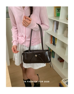 Detailed view of dark brown rectangular shoulder bag with bow and heart pendant