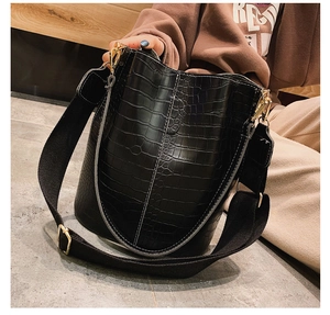 Detail of black crocodile pattern bucket bag with wide strap and gold hardware