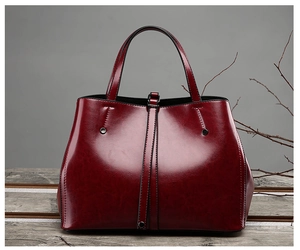Close-up of wine red vintage leather tote bag with polished finish on wooden table