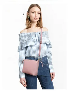 Pink crossbody bag with decorative side straps and gold buckle worn by model