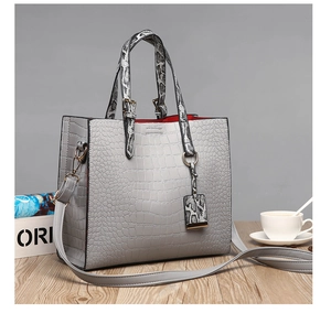 Detail of grey crocodile pattern tote with snake print handles and red interior lining