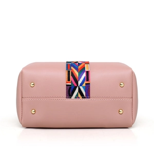 Bottom view of pink leather handbag showing gold protective feet and colorful striped webbing