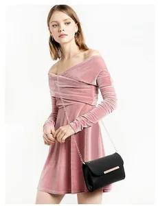 Fashionable black leather flap bag with gold chain strap shown on pink velvet dress