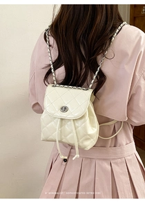 Detail of white quilted mini backpack with chain straps and metallic rotary buckle