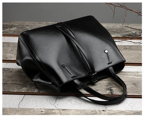 Vue détaillée du grand sac cabas en cuir noir avec rivets sur une surface en bois