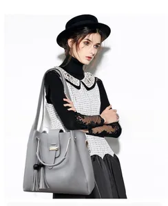 Detail of grey tote bag with tassel charm and wooden beads held by a fashion model