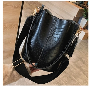 Detail of black crocodile pattern leather texture with golden metal hook and wide strap