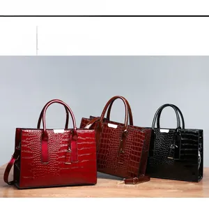 Detailed view of crocodile pattern tote bags in red, brown and black with metal accents