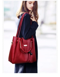Detail of red leather tote bag with gold circular handle and stylish tassel charm