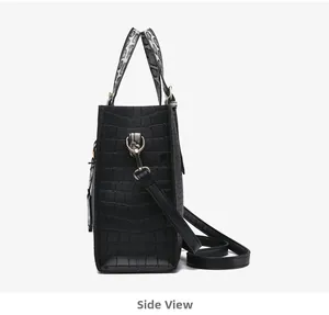 Side view of black faux crocodile tote bag with snakeskin handles and gusseted structure