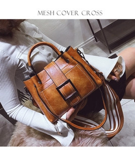 Close-up of brown bucket bag with striped wide shoulder strap and vintage square buckle