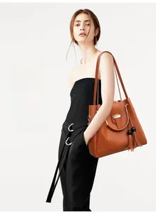 Close-up of caramel leather tote bag with tassels and decorative metal circular handles