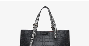 Detail of black crocodile texture bag with snakeskin pattern handles and metal buckles