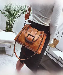 Close-up of brown vintage bucket bag featuring a colorful wide canvas strap and metal handle