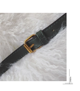 Detailed close-up of dark green litchi grain leather strap with a gold metal buckle