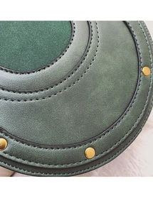 Dettaglio della borsa in pelle verde con cuciture in camoscio e rivetti dorati