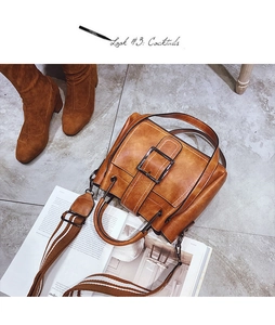 Close-up of vintage brown bucket bag with wide canvas strap and large metal buckle