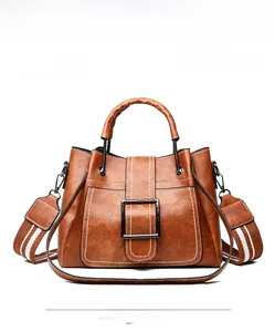 Detailed view of brown bucket bag with square buckle and woven shoulder strap