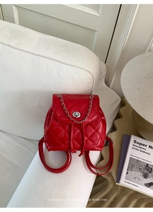 Close-up of red quilted mini backpack with silver metal chain and twist lock detail