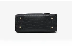 Detail view of the black faux crocodile leather bag bottom with golden metal studs