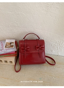 Detalle de la mochila de cuero PU rojo con adornos de lazos y letras del logo