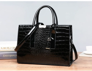 Close-up of black crocodile pattern patent leather handbag with gold metal hardware