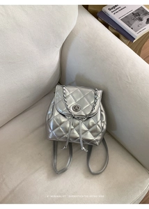 Detail of silver quilted backpack featuring metallic faux leather and metal turn-lock