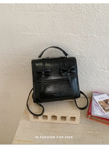 Detalle de la mochila de cuero PU negro con lazos decorativos y logotipo de la marca