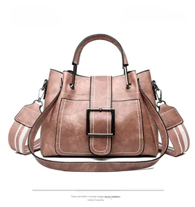 Detail of lotus pink bucket bag with white contrast stitching and wide striped strap