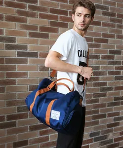 Detalle de la bolsa de viaje azul marino con correas naranjas y un compartimento lateral