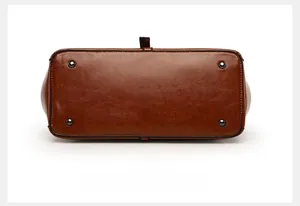 Detail shot of vintage brown leather tote bottom with four protective metal feet