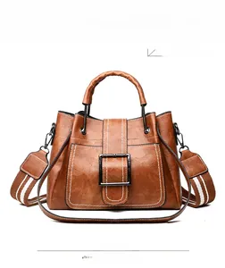 Front detail of caramel brown leather bucket bag with metal handle and contrast stitching