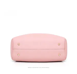 Pink Saffiano leather bag bottom view featuring four gold metal protective feet and fine stitching