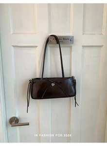 Detail of dark coffee leather shoulder bag with bow knot and silver heart pendant