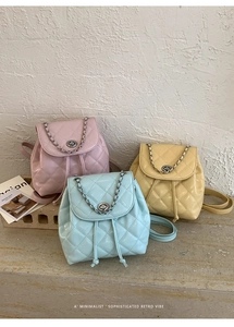 Close-up of quilted mini backpacks in pink, blue, and yellow with silver chain details