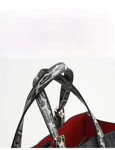 Detail of crocodile embossed handbag with snake skin pattern handles and gold buckles