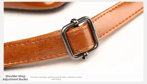 Close-up of adjustable brown leather shoulder strap with polished dark gray metal buckle