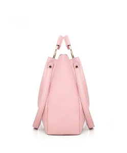 Detail view of pink crossbody bag with cross-grain texture and gold ring handle