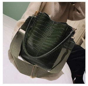 Detail of dark green crocodile texture bucket bag with olive green wide fabric strap
