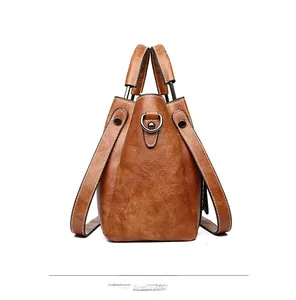 Side view of brown leather bucket bag showing textured finish and metal hardware