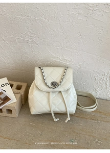 Close-up of quilted white leather backpack with silver chain and metal twist lock detail