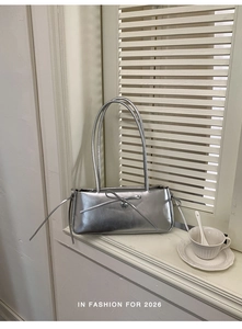 Silver metallic rectangular shoulder bag with bow detail and heart pendant on window sill