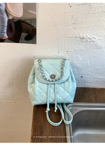 Close-up of mint green quilted leather backpack with silver rotating lock and chain detail