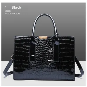 Close-up of black crocodile embossed patent leather tote with gold metal hardware