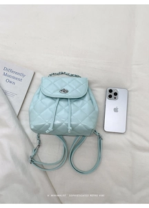 Detail of light green quilted backpack with silver twist lock and chic metal chain handle