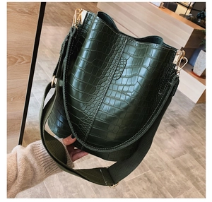 Close-up of crocodile texture on dark green bucket bag with gold-tone hardware