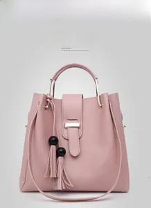 Detail of pink faux leather handbag with metal handles and black spherical tassels